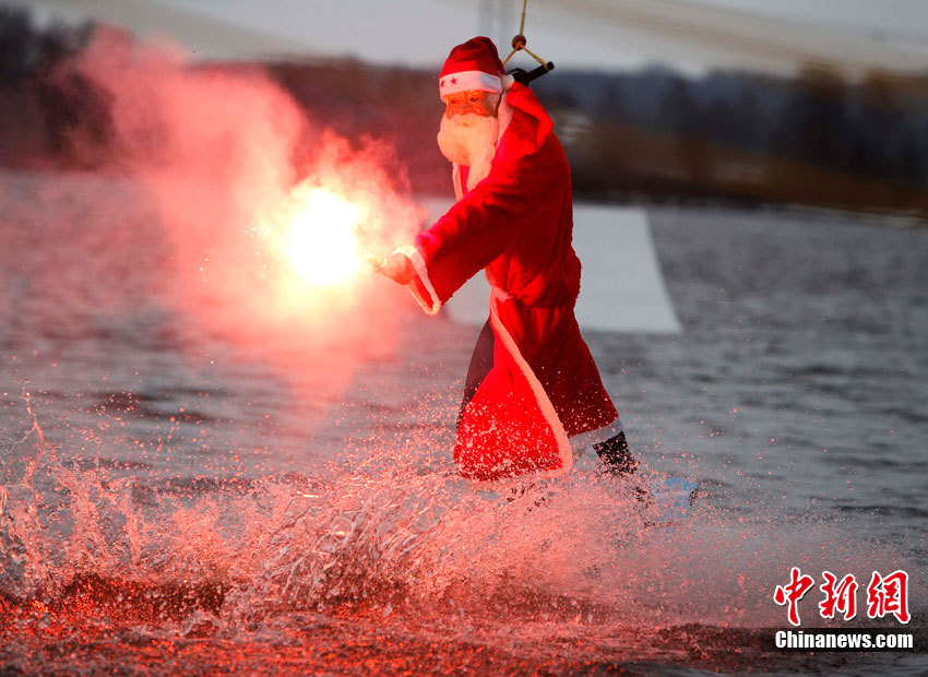A tourist dressed as Santa Claus surfs in a lake in Hamburg, Germany.(Photo/Chinanews.com)