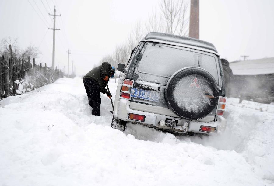 An electrical worker clears the snow that traps the car in Dongfanghong Town, northeast China's Heilongjiang Province, Dec. 4, 2012. The blizzard cut the power supply in many areas in Dongfanghong, disturbing the daily use of electricity for residents and enterprises. (Xinhua/Wang Kai)
