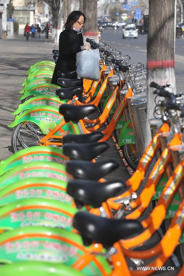 A woman picks up a public bike in a renting spot in Taiyuan, capital of north China's Shanxi Province, Dec. 5, 2012. Upon the end of November this year, there were 491 renting spots for public bikes in Taiyuan. A total of over 11,000 public bikes had been put into use. (Xinhua/Zhan Yan)