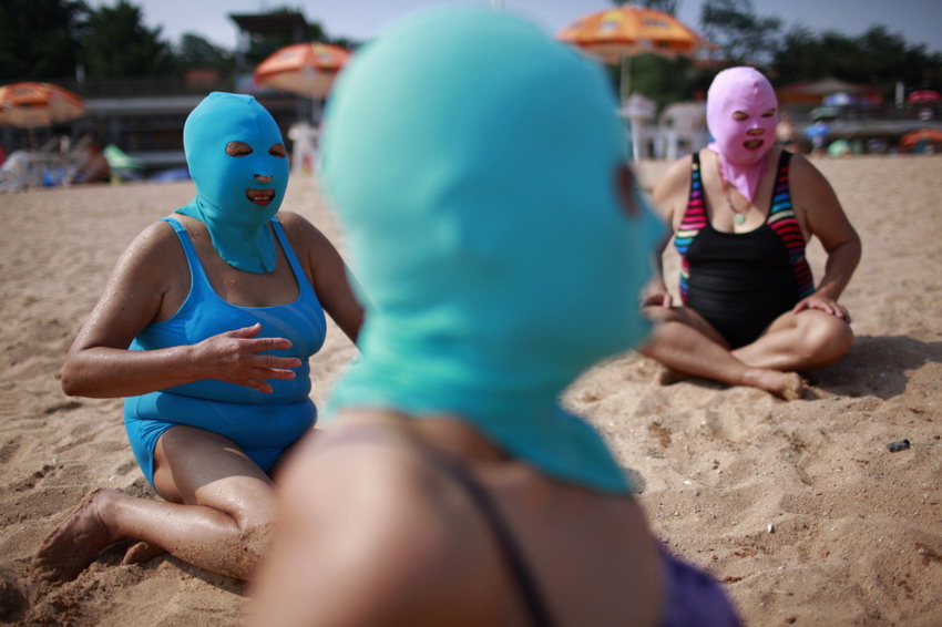 Ladies wear nylon masks to rest on beach in Qingdao, east China’s Shandong province, July 6, 2012. This mask invented seven years ago is used to block solar ray. (Reuters/Aly Song)