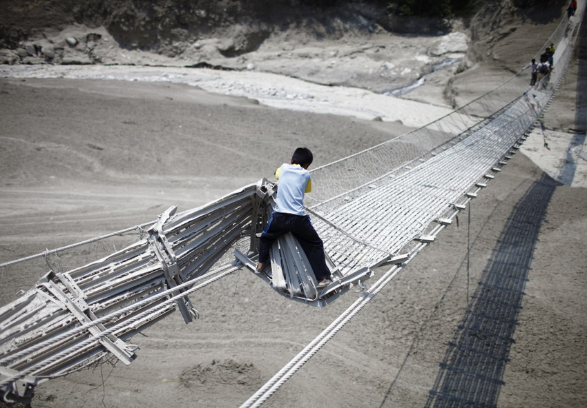 A boy tries to cross a suspension bridge that was damaged by flash floods in Nepal on May 6, 2012. (Reuters/Navesh Chitrakar)