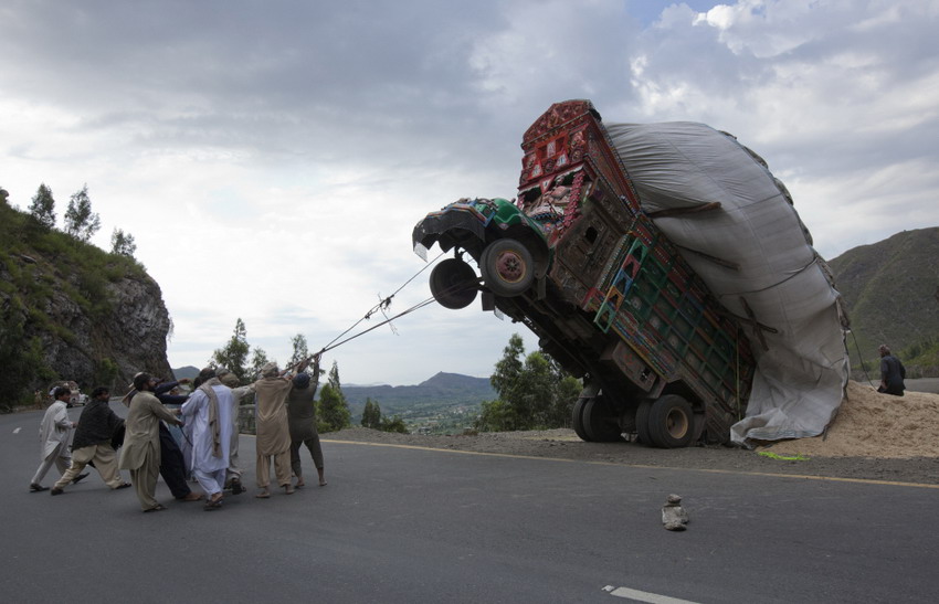 Men try to drag an overloaded truck back onto the road in northwest of Pakistan on April, 13, 2012.(Reuters/Mian Khursheed)