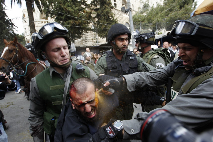 Israeli border police officers fire tear-gas while they detain an injured Palestinian demonstrator in a conflict on Land Day on March 30, 2012.  (Reuters/Ammar Awad)