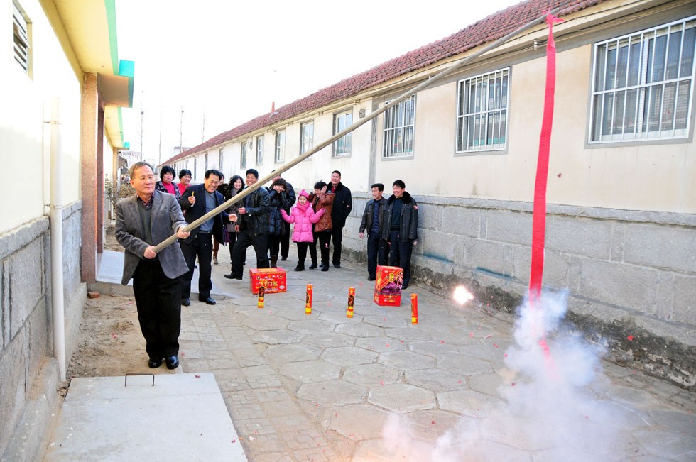 Kim Byungcho (front) sets off firecrackers in Dongli Village of Rushan, east China's Shandong Province, Jan. 22, 2012.(Xinhua Photo) 