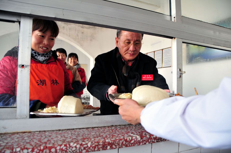 Kim Byungcho (R) has lunch with employees of his leather product company in Rushan, east China's Shandong Province, Jan. 19, 2012. (Xinhua Photo) 