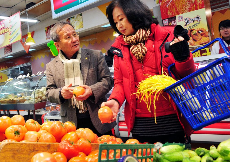 Kim Byungcho (L) and his wife buy vegetables at a supermarket in Rushan, east China's Shandong Province, Feb. 1, 2012. (Xinhua Photo) 