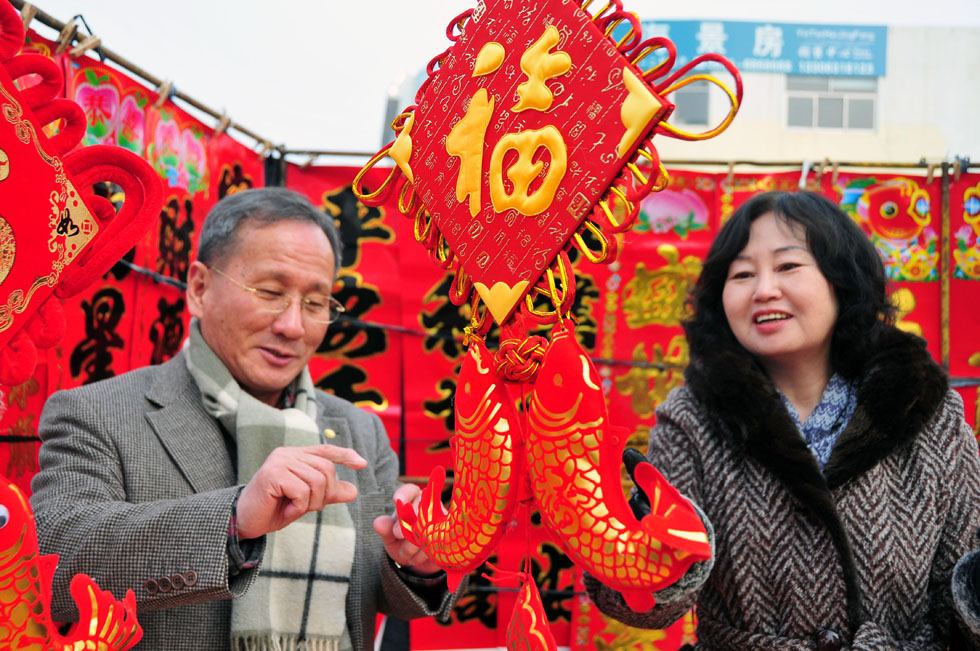 Kim Byungcho (L) and his wife buy festival decorations in a market of Rushan, east China's Shandong Province, Jan. 19, 2012.(Xinhua Photo) 