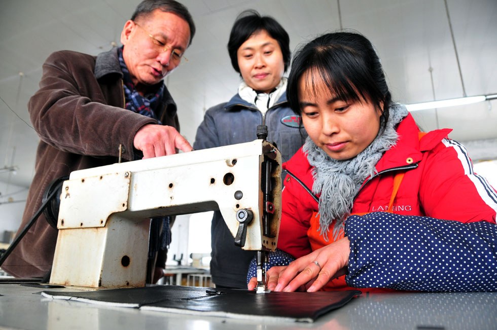 Kim Byungcho (L) instructs in a plant of his leather product company in Rushan, east China's Shandong Province, Jan. 18, 2012. (Xinhua Photo) 