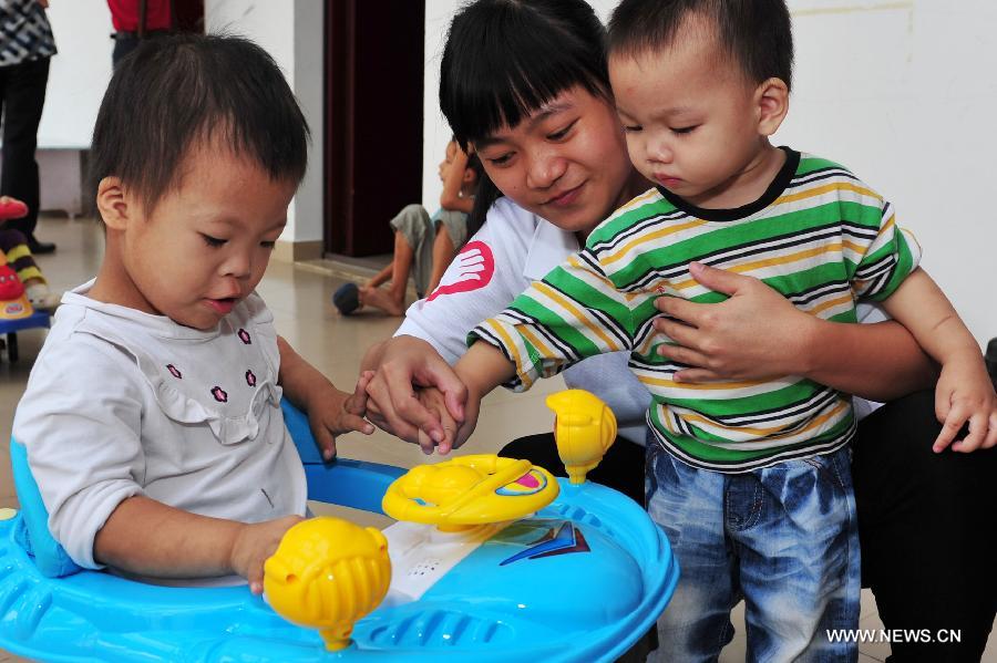 A volunteer plays with children at a welfare house in Sanya, capital of south China's Hainan Province, Dec. 5, 2012. Many Chinese volunteers make their contributions to the society on Wednesday, to mark the International Volunteer Day, which is an international observance designated by the United Nations since 1985. (Xinhua/Hou Jiansen) 