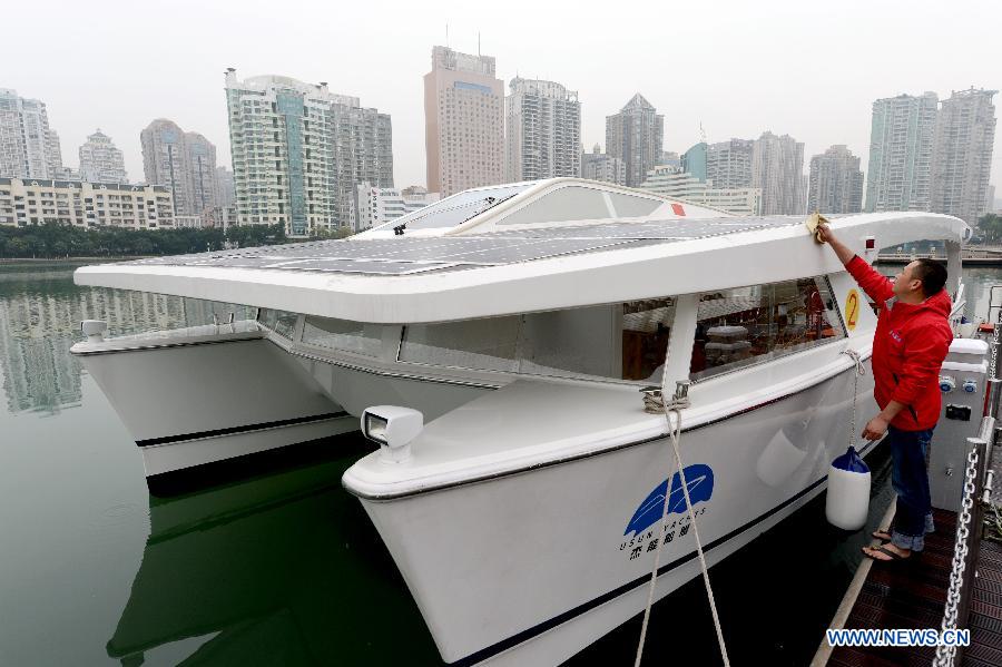 A working staff cleans a solar yacht on the Yundang Lake in Xiamen, southeast China's Fujian Province, Dec. 5, 2012. The 15-meter-long and 6-meter-wide solar yacht was put into use on Wednesday. The yacht can transform the collected solar energy into electricity to provide power supply for the facilities on board. (Xinhua/Zhang Guojun) 