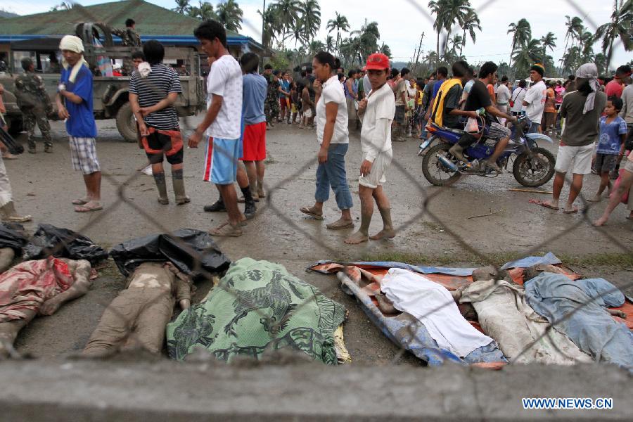 Residents walk past dead bodies in New Bataan town in southern province of Compostela Valley, the Philippines, on Dec. 5, 2012. The death toll from typhoon Bopha, locally known as Pablo, rises to 224, as Bopha continues to ravage several southern Philippine provinces. (Xinhua/Jeoffrey Maitem) 