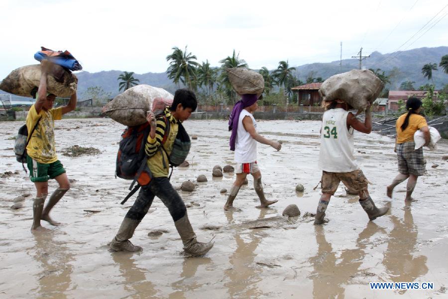 Homeless flood survivors walk on mud in New Bataan town in southern province of Compostela Valley, the Philippines, on Dec. 5, 2012. The death toll from typhoon Bopha, locally known as Pablo, rises to 224, as Bopha continues to ravage several southern Philippine provinces. (Xinhua/Jeoffrey Maitem) 