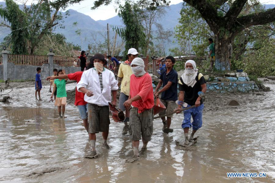 Residents carry a dead body in New Bataan town in southern province of Compostela Valley, the Philippines, on Dec. 5, 2012. The death toll from typhoon Bopha, locally known as Pablo, rises to 224, as Bopha continues to ravage several southern Philippine provinces. (Xinhua/Jeoffrey Maitem) 