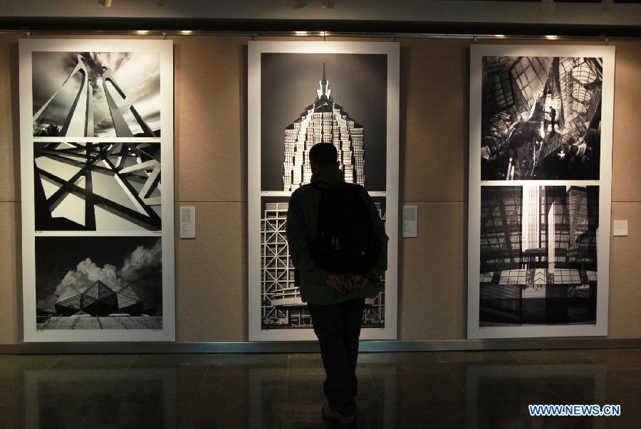 A man looks at pictures displayed at a photo exhibition on China's steel structure in the city library of east China's Shanghai Municipality, Dec. 5, 2012. The exhibition which kicked off on Wednesday will last until Dec. 9, 2012. (Xinhua/Ding Ting)
