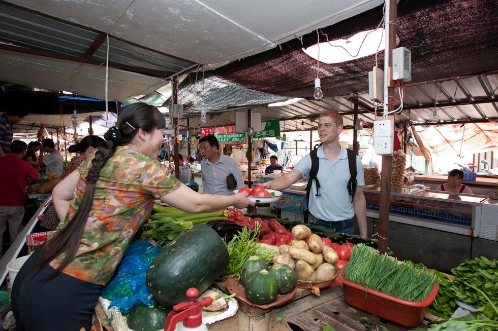 Florian Paillard (R) buys vegetables at a wet market after work in Hefei, capital of east China's Anhui Province, May 18, 2012. (Xinhua/Liu Junxi)