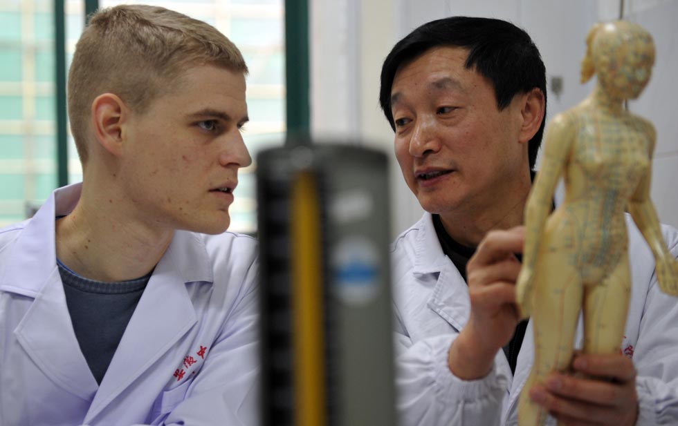 Florian Paillard (L) listens as his tutor Cai Shengchao explains the human's meridian system at the Acupuncture and Moxibustion Hospital of Anhui University of Traditional Chinese Medicine in Hefei, capital of east China's Anhui Province, Feb 13, 2012.(Xinhua/Liu Junxi)