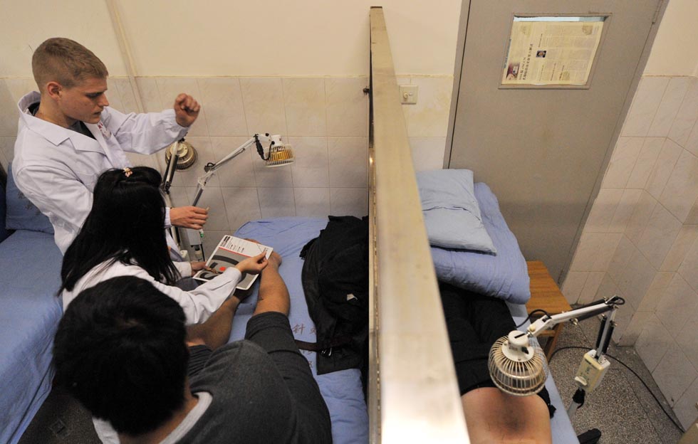 Florian Paillard (back) gives an acupuncture treatment to a patient at the Acupuncture and Moxibustion Hospital of Anhui University of Traditional Chinese Medicine in Hefei, capital of east China's Anhui Province, Feb. 13, 2012.(Xinhua/Liu Junxi)