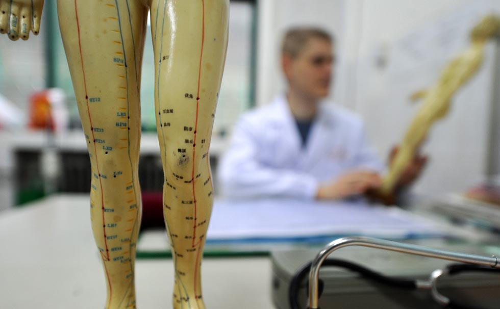 Florian Paillard looks at a meridian model at the Acupuncture and Moxibustion Hospital of Anhui University of Traditional Chinese Medicine in Hefei, capital of east China's Anhui Province, Feb. 13, 2012.(Xinhua/Liu Junxi)
