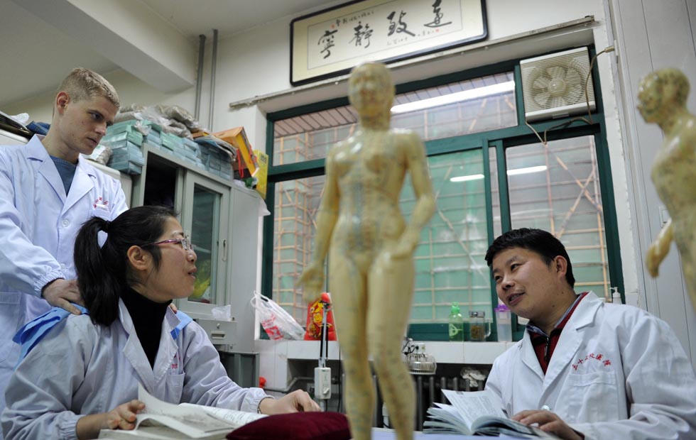 Florian Paillard (1st L) listens as his colleagues discuss academic issues at the Acupuncture and Moxibustion Hospital of Anhui University of Traditional Chinese Medicine, in Hefei, capital of east China's Anhui Province, Feb. 13, 2012.(Xinhua Photo)