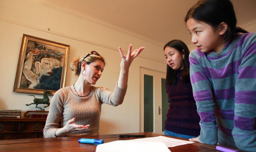 Elyse Ribbons (L) talks about a script for young actresses at her home in Beijing, China, on Dec. 11, 2011.(Xinhua/Hou Dongtao)
