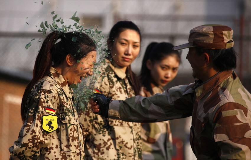 An instructor from a security guard company smashes a bottle over a female trainee’s head during a training session for China’s first female bodyguard in Beijing, China, Jan 13, 2012. (Reuters/David Gray)
