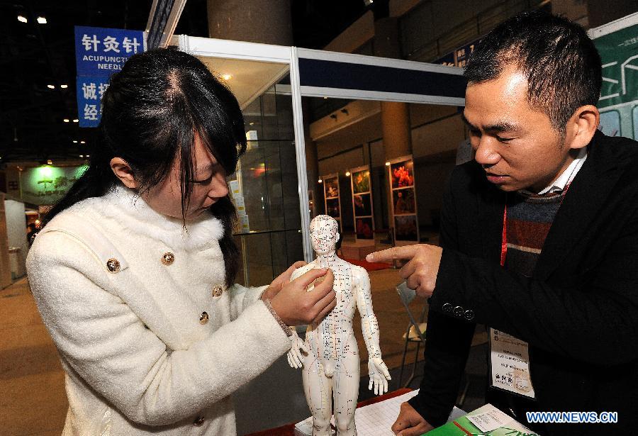 An exhibitor introduces acupuncture to a woman during the China Traditional Chinese Medicine Culture and Industry Expo 2012 in Beijing, capital of China, Dec. 6, 2012. The three-day event kicked off at Beijing Exhibition Center on Thursday. (Xinhua/He Junchang) 