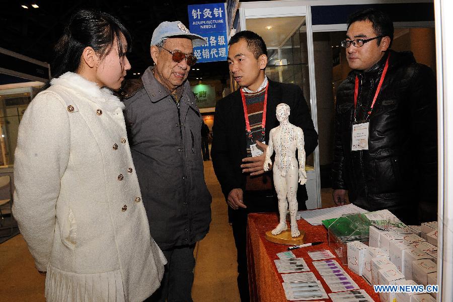 Exhibitors introduce acupuncture to visitors during the China Traditional Chinese Medicine Culture and Industry Expo 2012 in Beijing, capital of China, Dec. 6, 2012. The three-day event kicked off at Beijing Exhibition Center on Thursday. (Xinhua/He Junchang)