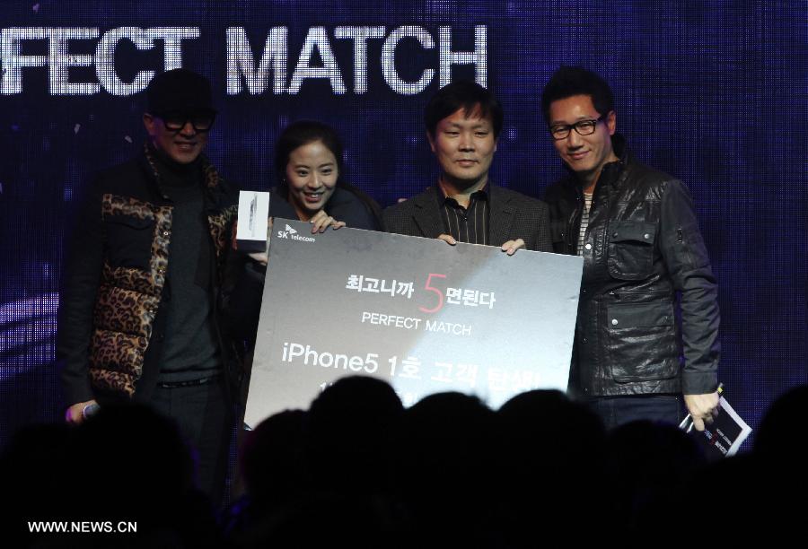 The first customer South Korean Ahn Hea-jin (2nd L) poses with her iPhone 5 during the iPhone 5 launch event in Seoul, South Korea, Dec. 7, 2012. (Xinhua/Park Jin hee)