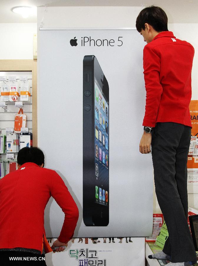 Staff hang a banner of iPhone 5 at a SK Telecom store in Seoul, South Korea, Dec. 7, 2012. (Xinhua/Park Jin-hee)