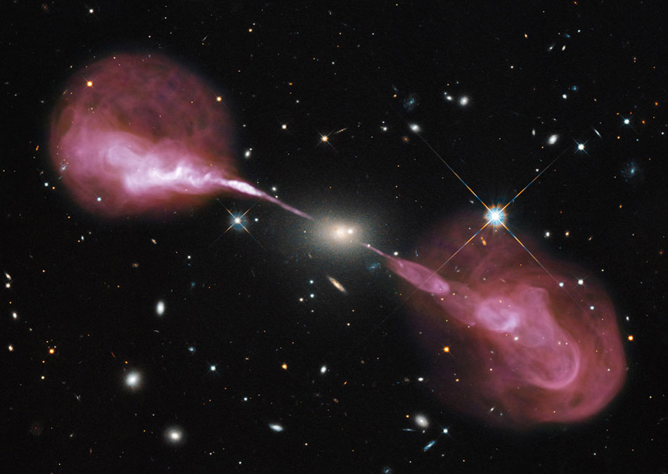 Plasma Jets from Radio Galaxy Hercules A. Why does this galaxy emit such spectacular jets? No one is sure, but it is likely related to an active supermassive black hole at its center. The galaxy at the image center, Hercules A, appears to be a relatively normal elliptical galaxy in visible light. (Photo/ NASA)