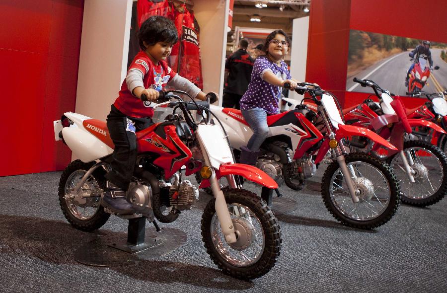 Two children take a test ride during the 2012 Toronto Motorcycle Show at the Metro Toronto Convention Centre in Toronto, Canada, Dec. 8, 2012. The three-day event displays hundreds of new 2013 motorcycles, scooters from the world's top manufacturers from Dec. 7 to 9 this year. (Xinhua/Zou Zheng) 