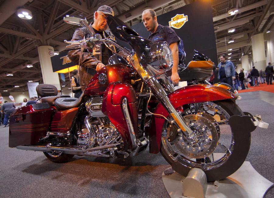 Visitors watch a displayed motorcycle during the 2012 Toronto Motorcycle Show at the Metro Toronto Convention Centre in Toronto, Canada, Dec. 8, 2012. The three-day event displays hundreds of new 2013 motorcycles, scooters from the world's top manufacturers from Dec. 7 to 9 this year. (Xinhua/Zou Zheng) 