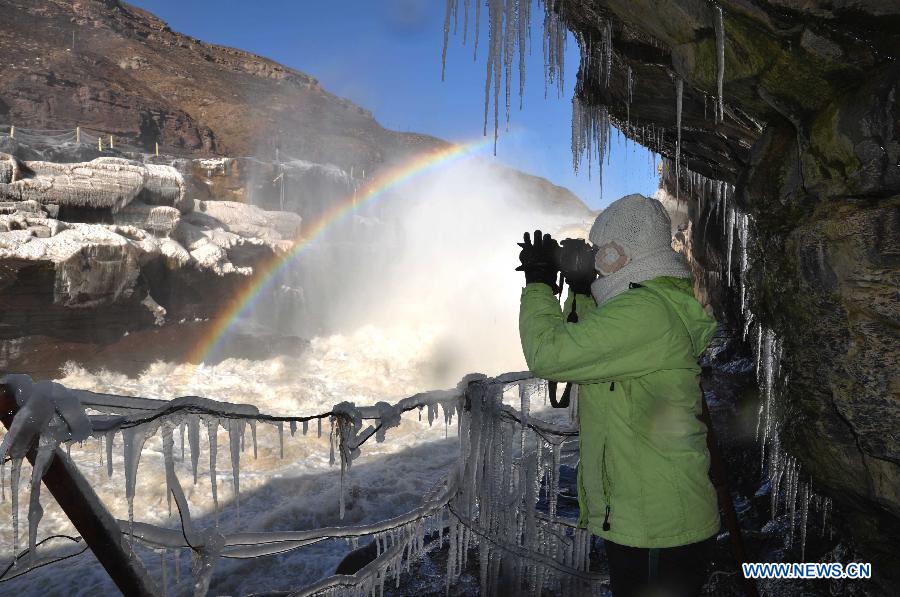 A visitor takes photos of a rainbow over the Hukou Waterfalls, a section of the middle reaches of the Yellow River, in Linfen, north China's Shanxi Province, Dec. 8, 2012. Icicles have been formed on the Hukou Waterfalls recently due to low temperature. Hukou Waterfalls are located on the border of Shanxi and northwest China's Shaanxi Province. (Xinhua/Lv Guiming)
