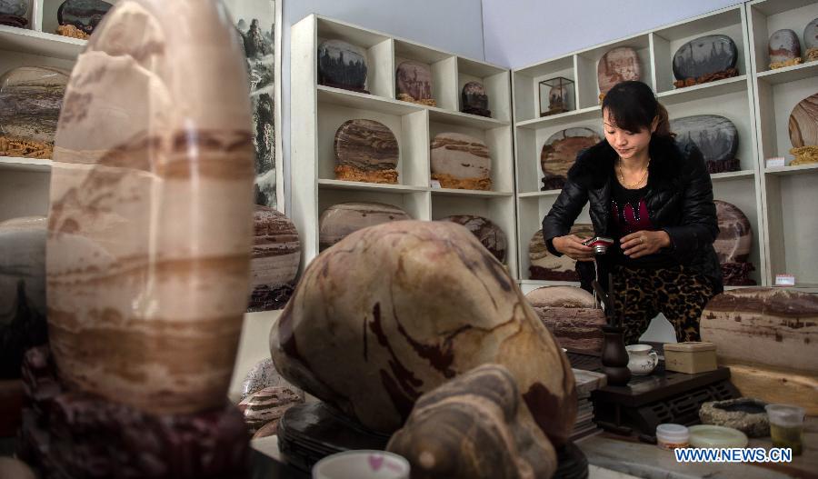 A woman owner of a finished stone store takes photos of stones in Changyang Tujia Autonomous County, central China's Hubei Province, Dec. 8, 2012. Located close to the Qingjiang River, the county is abundant in "Qingjiang Stone", of which natural colors and grains enable people here to develop it into ornamental stones. The stone industry has provided over 35,000 jobs for the people in the county, contributing greatly to the local economic development. (Xinhua/Cheng Min) 