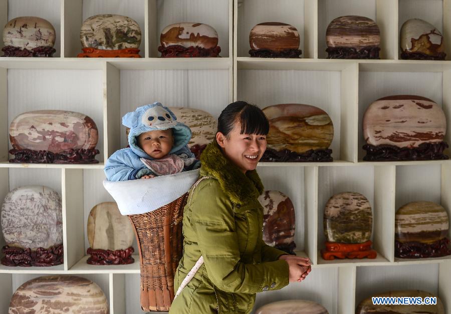 A woman owner of a finished stone store waits for customers in Changyang Tujia Autonomous County, central China's Hubei Province, Dec. 8, 2012. Located close to the Qingjiang River, the county is abundant in "Qingjiang Stone", of which natural colors and grains enable people here to develop it into ornamental stones. The stone industry has provided over 35,000 jobs for the people in the county, contributing greatly to the local economic development. (Xinhua/Cheng Min)