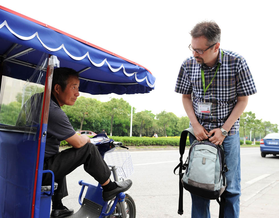Anatoly Burov (R) makes inquires of a motorcycle driver about the price in Shanghai, east China, May 7, 2012. (Xinhua/Lai Xinlin) 