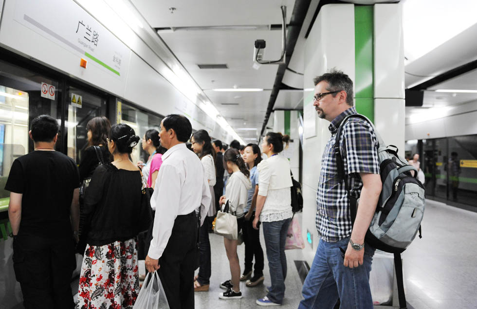 Anatoly Burov (R, front) queues to get on a subway train in Guanglan Road Station of Shanghai, east China, May 7, 2012. (Xinhua/Lai Xinlin) 