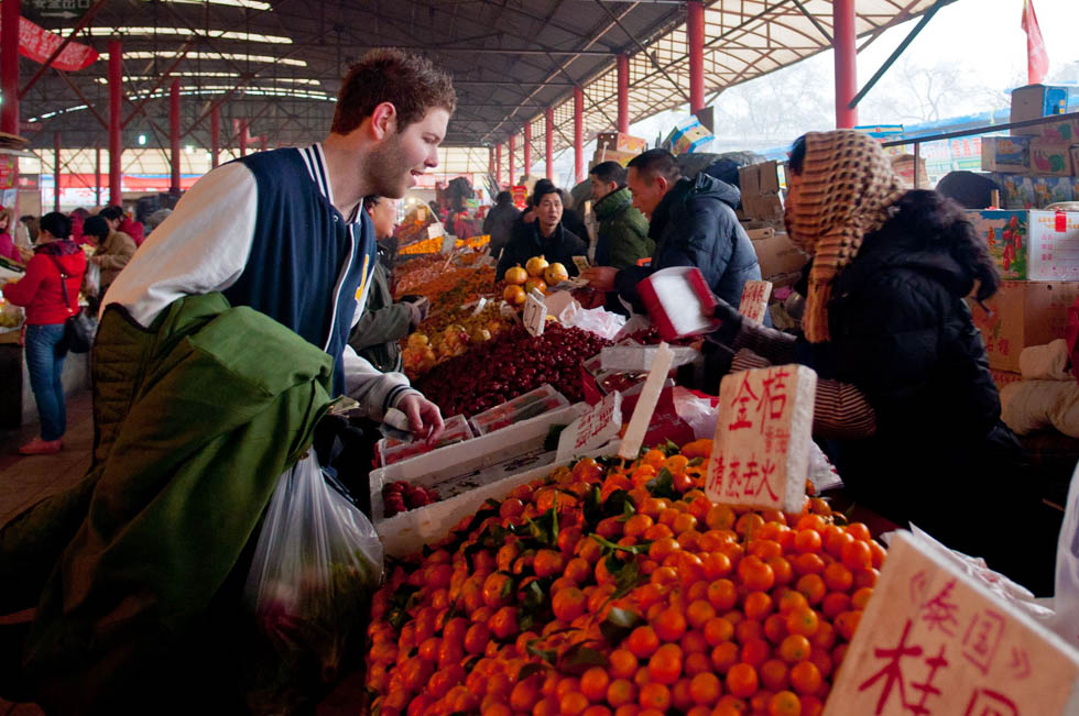 Jamie (L, Front) buys fruits at a market in Ping'anli, a neighbourhood in Beijing, capital of China, Dec. 5, 2011. (Xinhua/Liu Jinhai) 