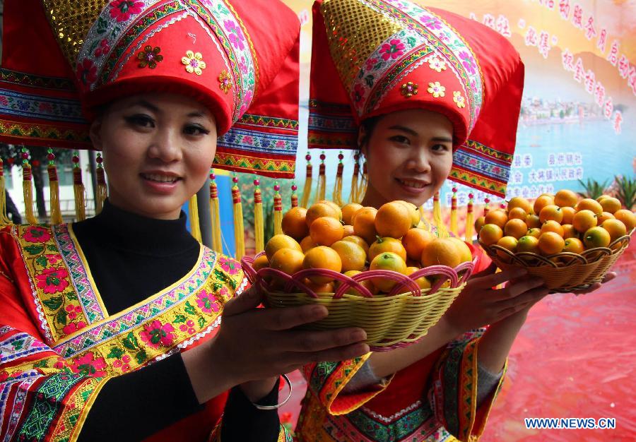Two women present cumquat during a contest for cumquat in Dajiang Town of Rong'an County, Liuzhou City, south China's Guangxi Zhuang Autonomous Region, Dec. 10, 2012. Cumquat planting has become a major income source for local farmers in Rong'an. (Xinhua/Long Linzhi)