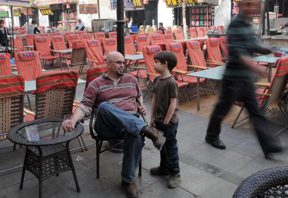 Kevin Gilley (L) talks with his son Nathan outside his coffee house in Dunhuang, northwest China's Gansu Province, April 27, 2012. 