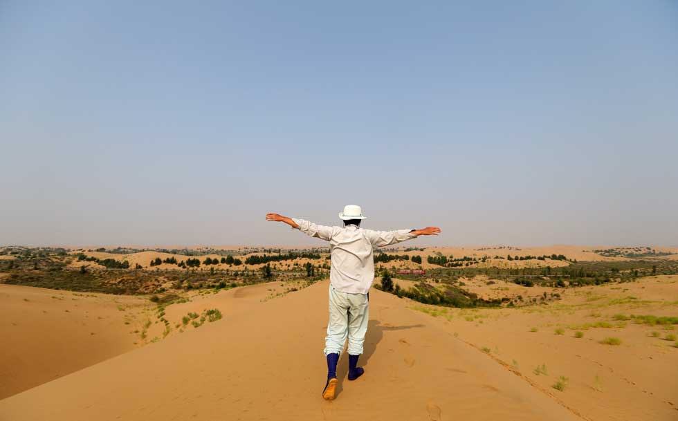 Mase Hiroki waves to the oasis in the desert in Engebei, Ordos,north China's Inner Mongolia Autonomous Region, Aug. 26, 2012.(Xinhua/Xie Xiudong)