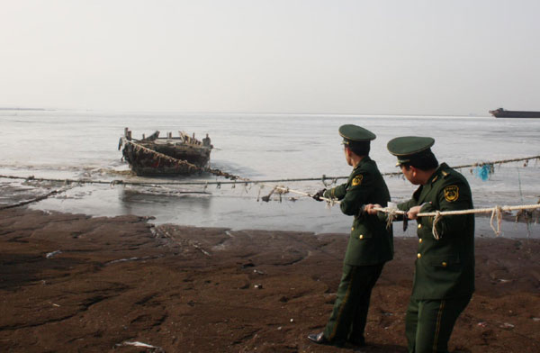 Frontier soldiers pull a boat to safety from the icy sea off Laizhou Bay in East China's Shandong province December 10, 2012. (Photo/chinadaily.com.cn)