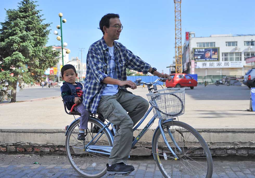 Otaki Takashi carries his three-year-old son with a bicycle in Ganqika Township of Horqin Left Wing Rear Banner of Tongliao City, north China's Inner Mongolia Autonomous Region, June 12, 2012. (Xinhua/Ren Junchuan)
