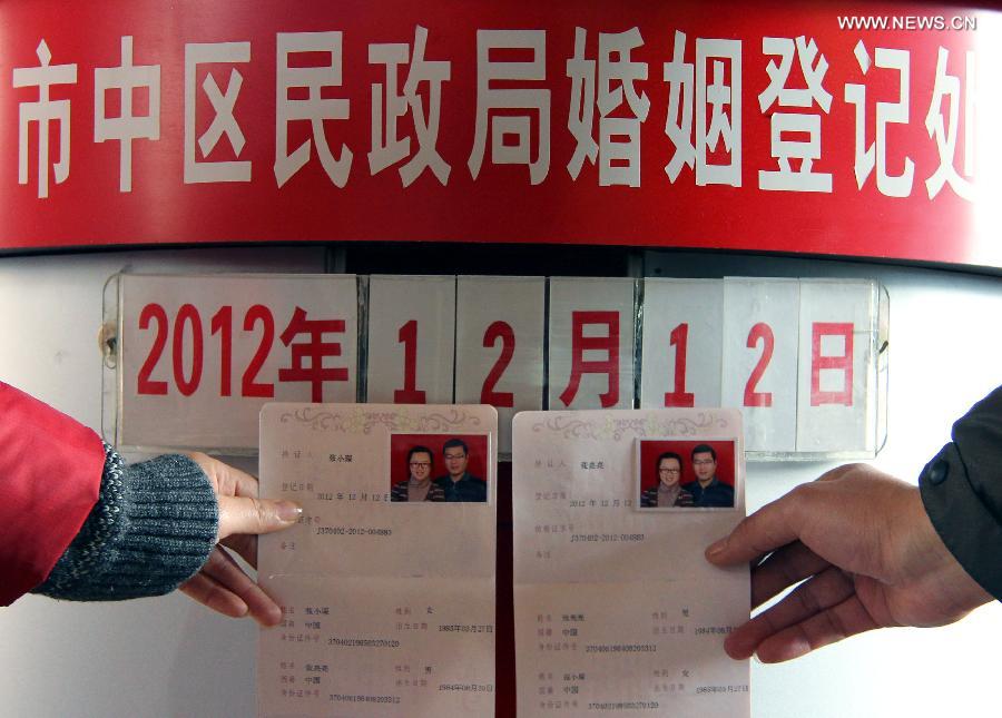 A young couple show their marriage certificates at a civil affairs bureau in Zaozhuang City, east China's Shandong Province, Dec. 12, 2012. Young couples across the country rushed to get married on Dec, 12, 2012, or 12/12/12, hoping that the "triple 12 day" will bring them good luck. In Chinese, the number 12 is pronounced like "Yao Ai", meaning "To Love" in English. (Xinhua/Sun Zhongzhe)