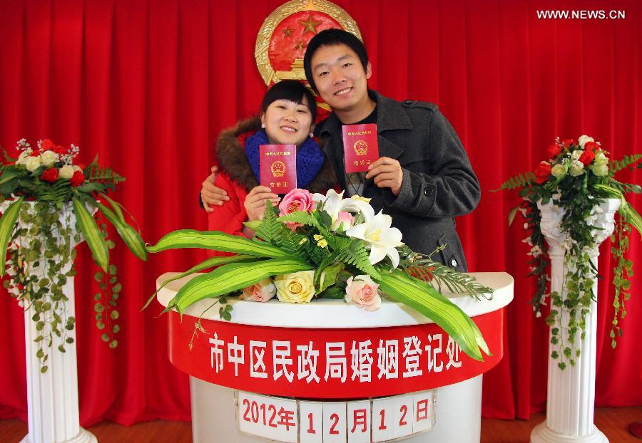 A young couple show their marriage certificates at a civil affairs bureau in Zaozhuang City, east China's Shandong Province, Dec. 12, 2012. Young couples across the country rushed to get married on Dec, 12, 2012, or 12/12/12, hoping that the "triple 12 day" will bring them good luck. In Chinese, the number 12 is pronounced like "Yao Ai", meaning "To Love" in English. (Xinhua/Sun Zhongzhe)