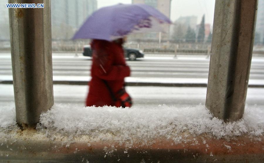 A pedestrian walks in snow in Tiantongyuan, Beijing, capital of China, Dec. 12, 2012. A snow hit China's capital city on Wednesday. (Xinhua/Yin Bogu)