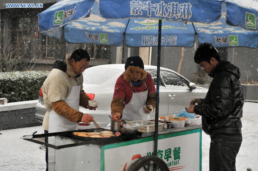 Two breakfast vendors do business in snow in Beijing, capital of China, Dec. 12, 2012. A snow hit China's capital city on Wednesday. (Xinhua/Sun Ruibo)