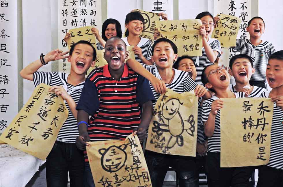 Senegalese merchant Mamadou Sall's first son Muhammed (2nd L, front) and his Chinese classmates present their drawing works at Yiwu Qunxing Private School in Yiwu, east China's Zhejiang Province, May 25, 2010.(Xinhua/Tan Jin) 
