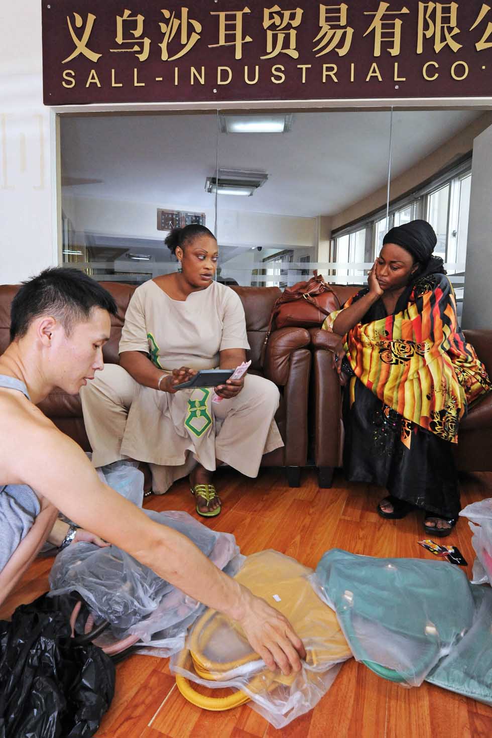 Senegalese merchant Mamadou Sall's wife Fatima (C) bargains with a Gambian businesswoman in Sall-Industrial Co., Ltd. in Yiwu, east China's Zhejiang Province, July 15, 2012. (Xinhua/Tan Jin) 
