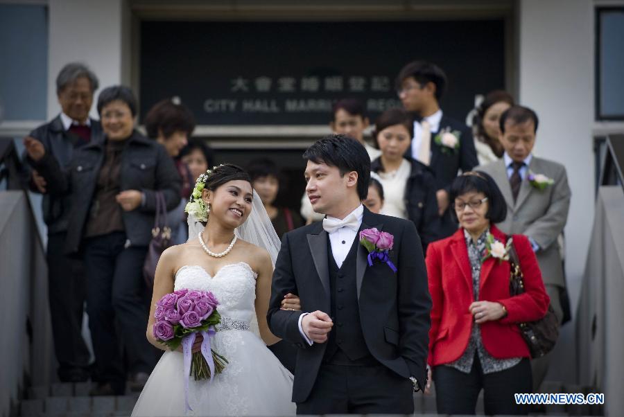 A newly married couple steps out of the marriage registration hall in Hong Kong, south China, Dec. 12, 2012. A total of 696 couples flocked to tie the knot on Dec. 12, 2012, or 12/12/12, which sounds like "will love/will love/will love" in Chinese. (Xinhua/Lui Siu Wai)